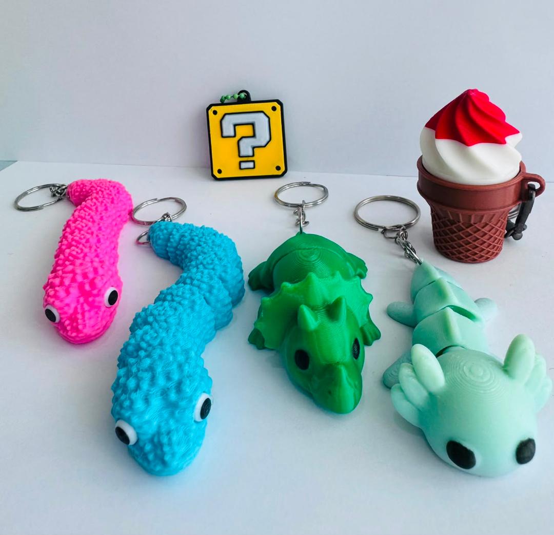 3D printed character keychains including eel fidgets, a mystery block, an ice cream charm, a triceratops and an axolotl